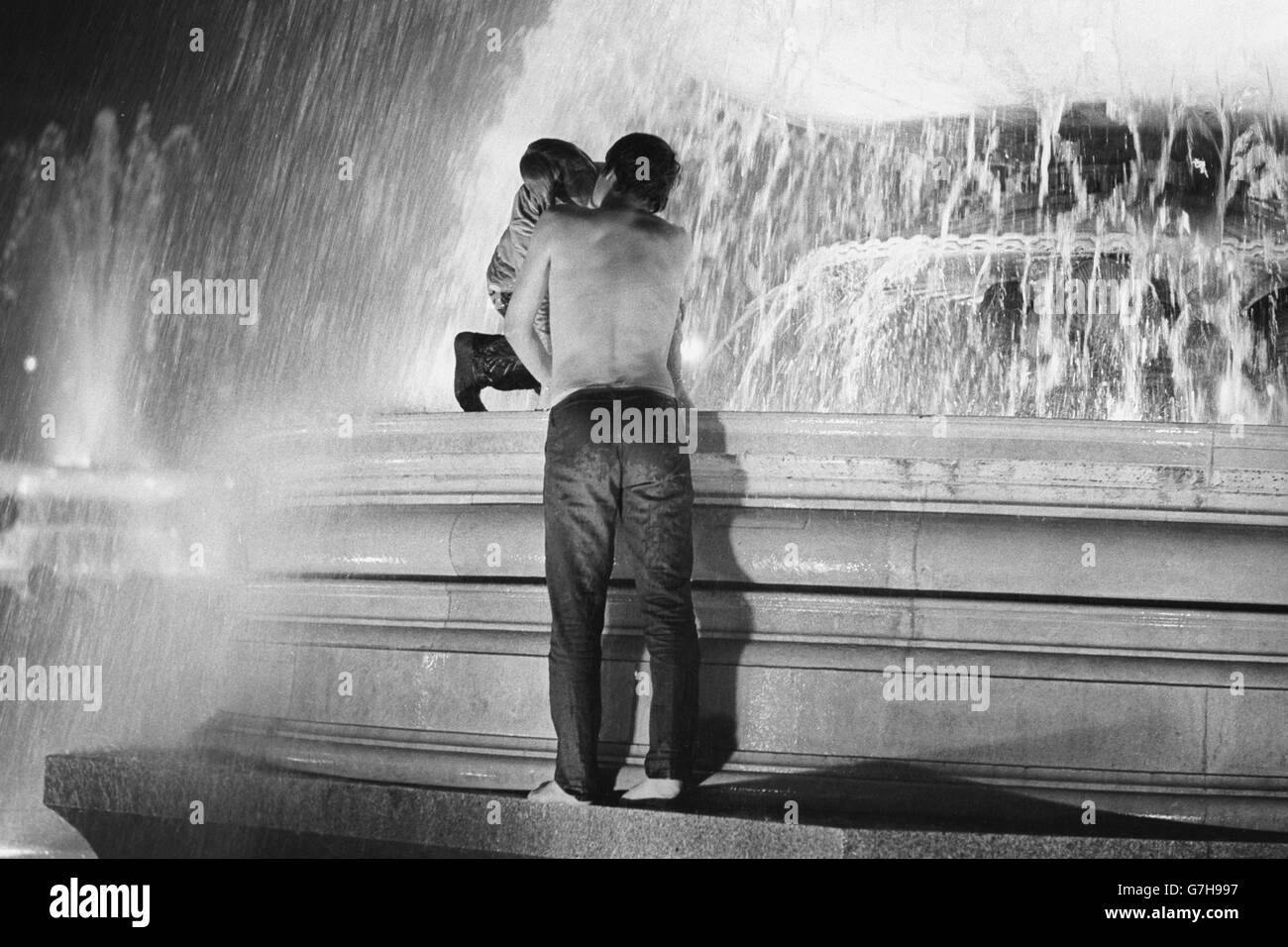 As 1968 fades away, new year antics break out in Trafalgar Square, London. two revellers, one stripped to the waist, celebrate the new year with a kiss. Stock Photo