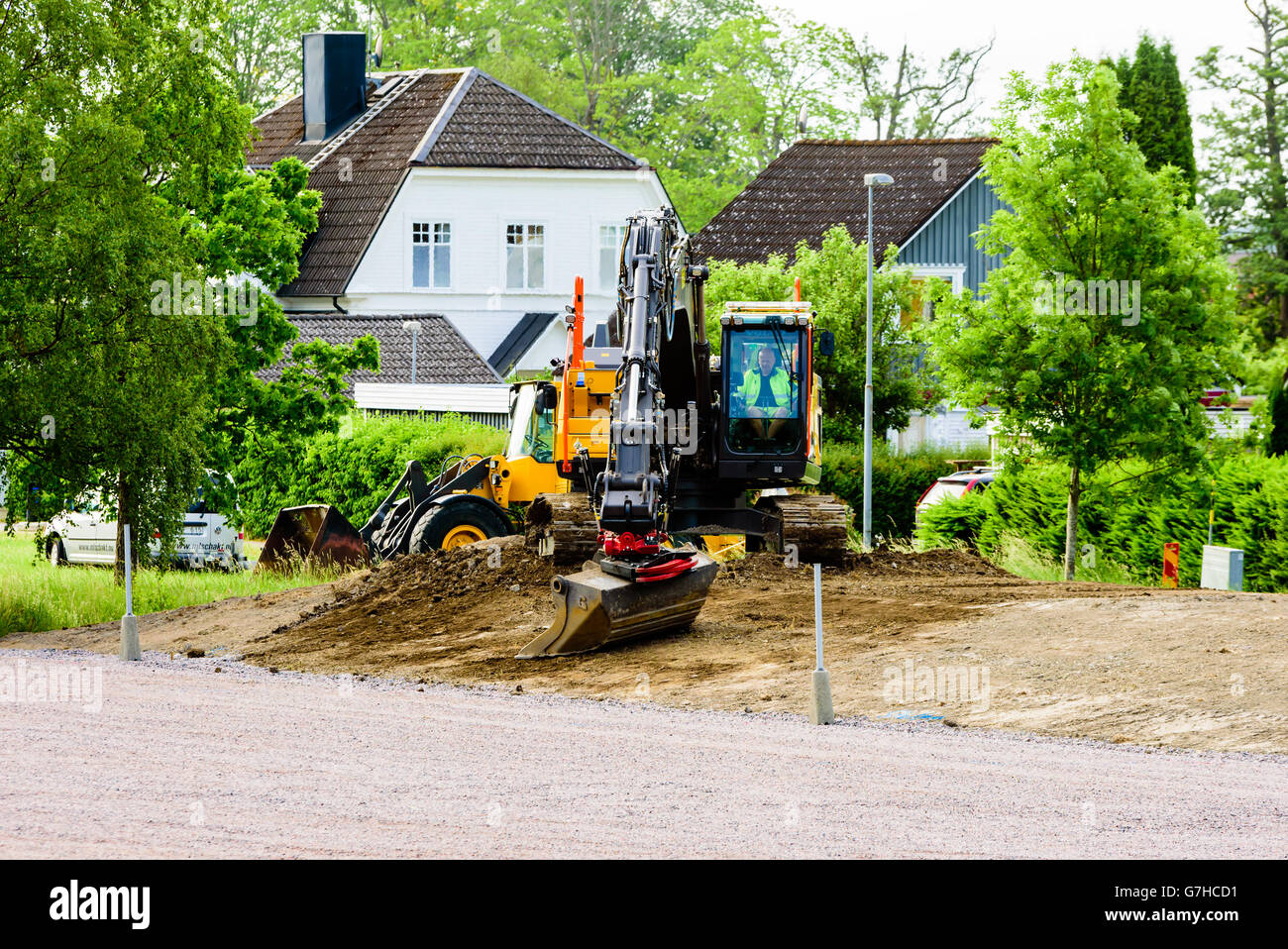 Soderkoping, Sweden - June 20, 2016: Excavator doing final adjustments to a dirt slope. Driver inside the cabin. Stock Photo