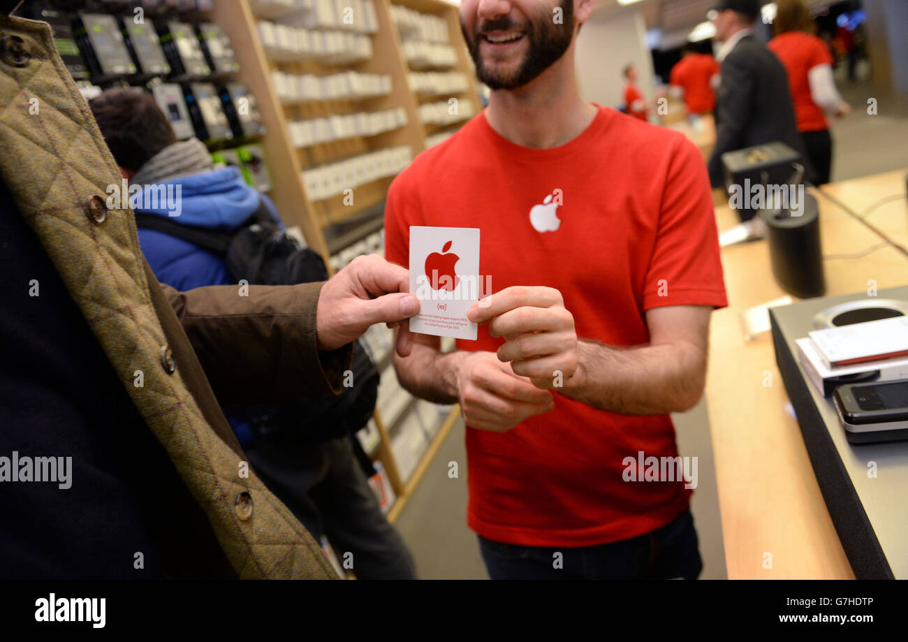 An Apple employee hands-out a red Apple sticker following a purchase as the Apple store in Regent Street, London, displays red logos in recognition of World Aids Day as Apple stores across the globe go red, with a red logo and other red elements in store. Stock Photo
