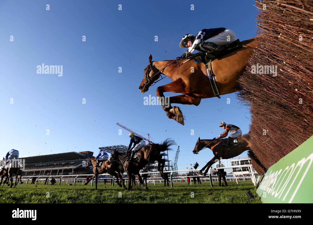 Runners and riders jump a fence the Caspian Caviar Gold Cup during day two of The International at Cheltenham Racecourse, Cheltenham. Stock Photo