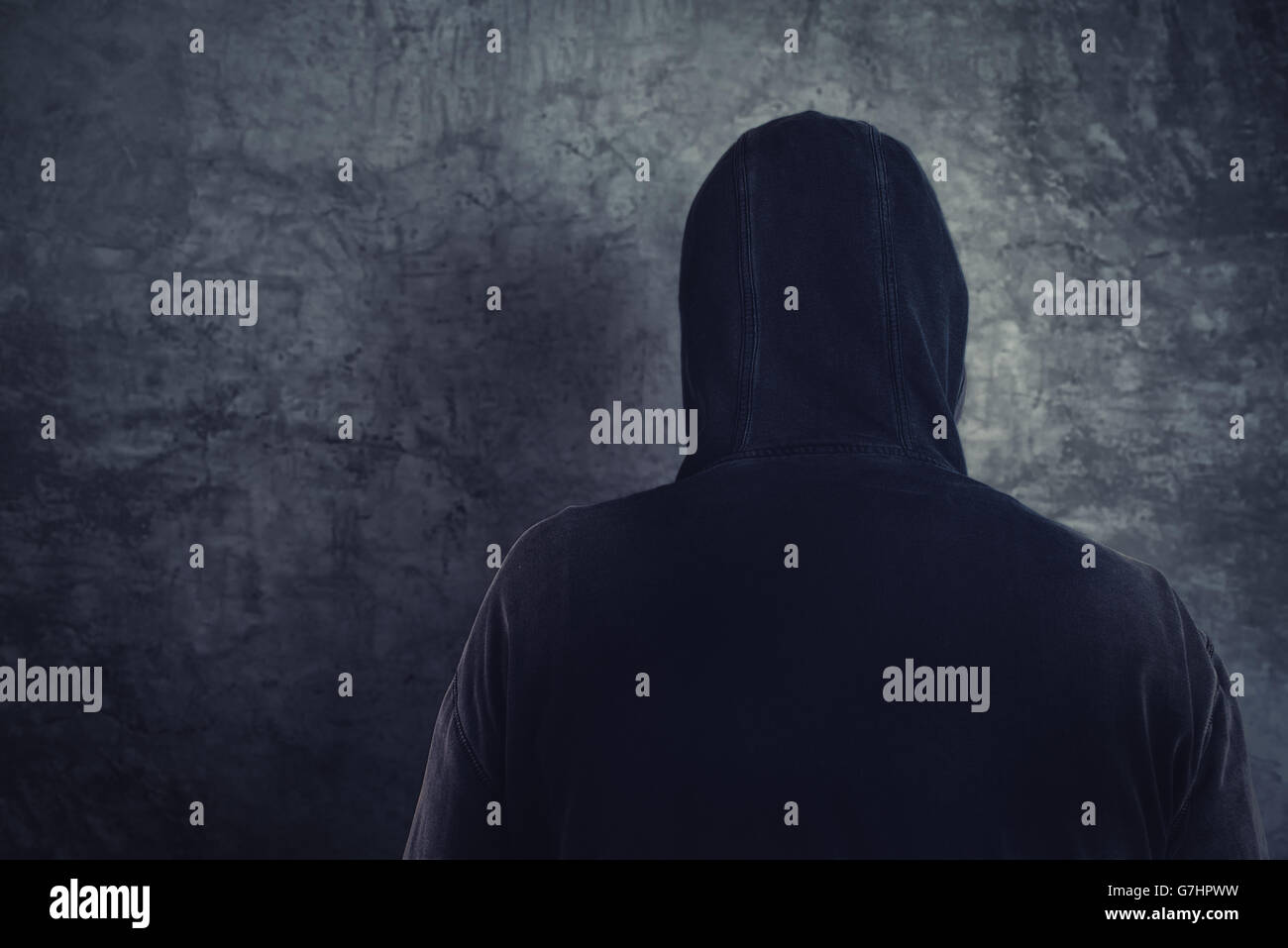 Unrecognizable hooded soccer hooligan from behind, spooky criminal