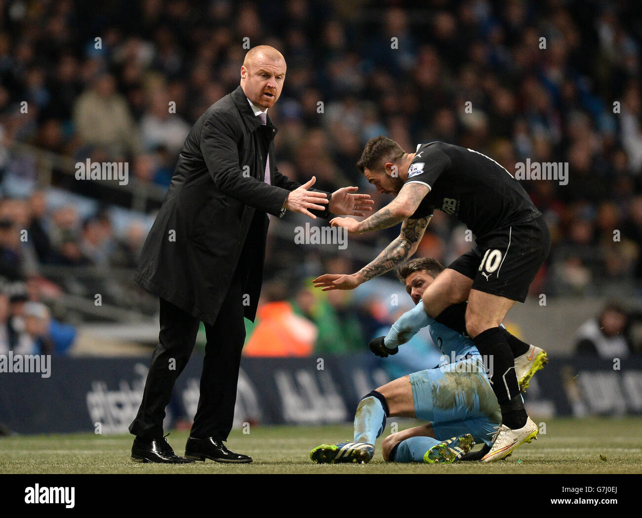 Burnley manager Sean Dyche (left) has to watch his step as Burnley's Danny Ings and Manchester City's Martin Demechellis tackle on the touchline during the Barclays Premier League match at the Etihad Stadium, Manchester. Stock Photo