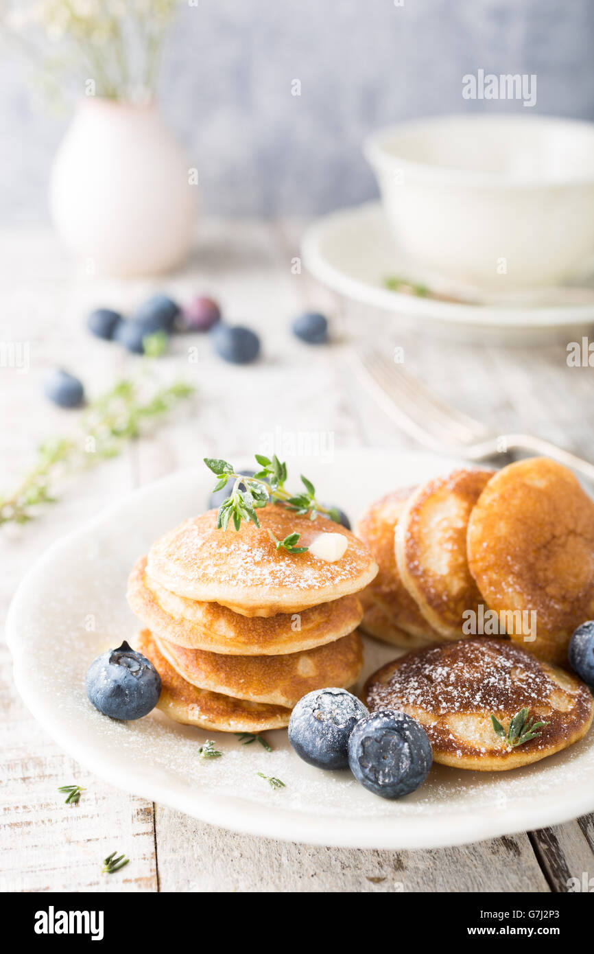 Dutch mini pancakes called poffertjes with blueberries and thyme, sprinkled with powdered sugar. Healthy food concept. Stock Photo