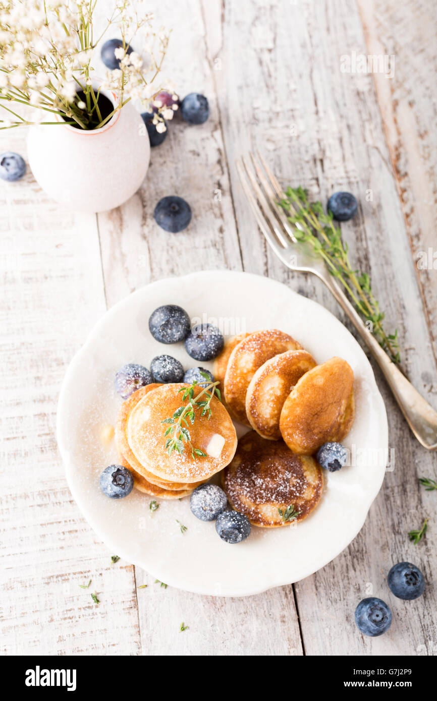 Dutch mini pancakes called poffertjes with blueberries and thyme, sprinkled with powdered sugar. Healthy food concept. Stock Photo