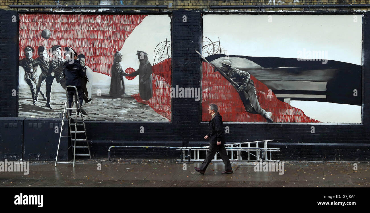 German artist Sokar Uno puts the finishing touches to a graffiti artwork with UK artists Zadok and Ninth Seal (not pictured), at the Shoreditch Art Wall in east London, which has been created on behalf of Visit Flanders to commemorate the 100th anniversary of the Christmas Truce of World War One. Stock Photo