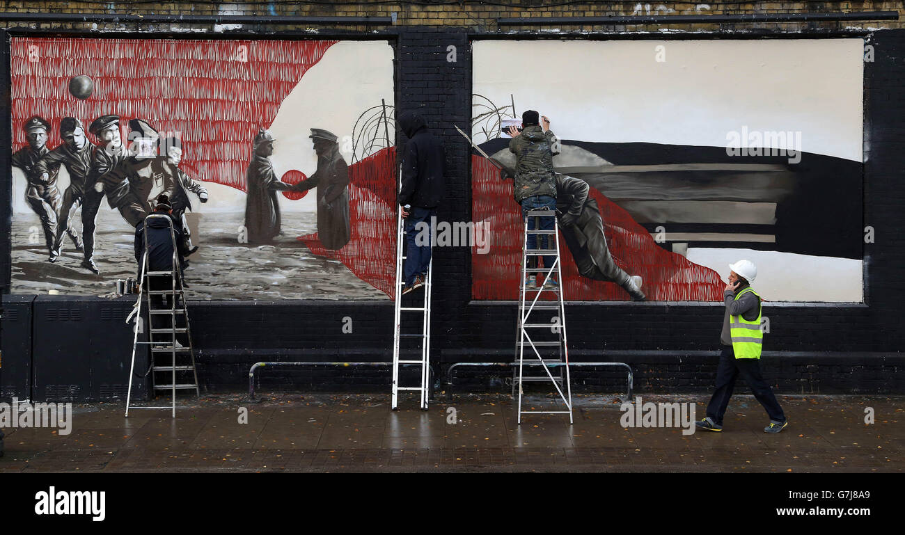 German artist Sokar Uno (left) puts the finishing touches to a graffiti artwork with UK artists Zadok and Ninth Seal, at the Shoreditch Art Wall in east London which has been created on behalf of Visit Flanders to commemorate the 100th anniversary of the Christmas Truce of World War One. Stock Photo