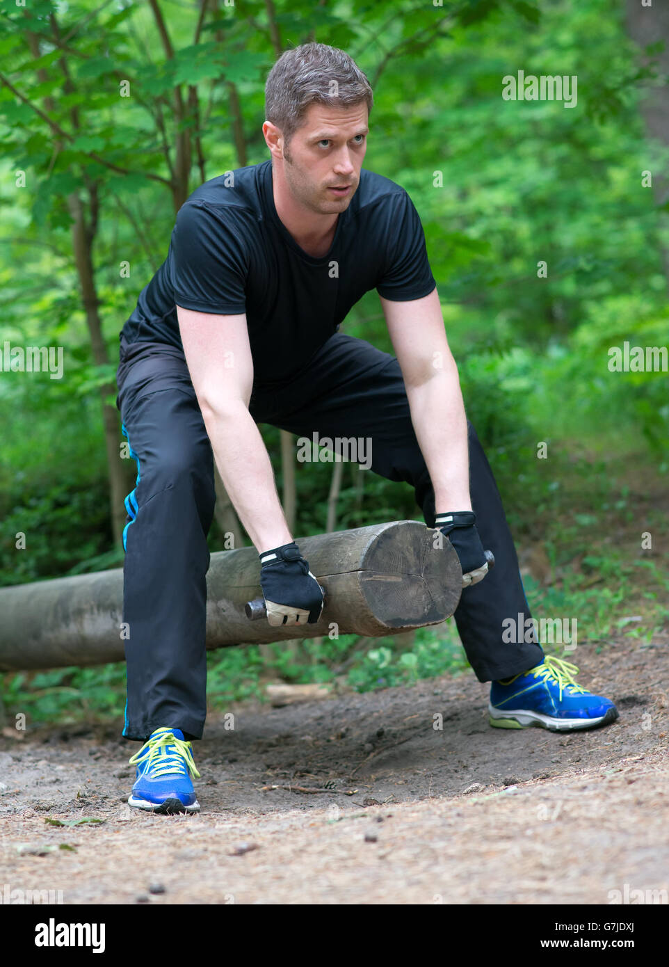 Man lifting log in the forest. Stock Photo