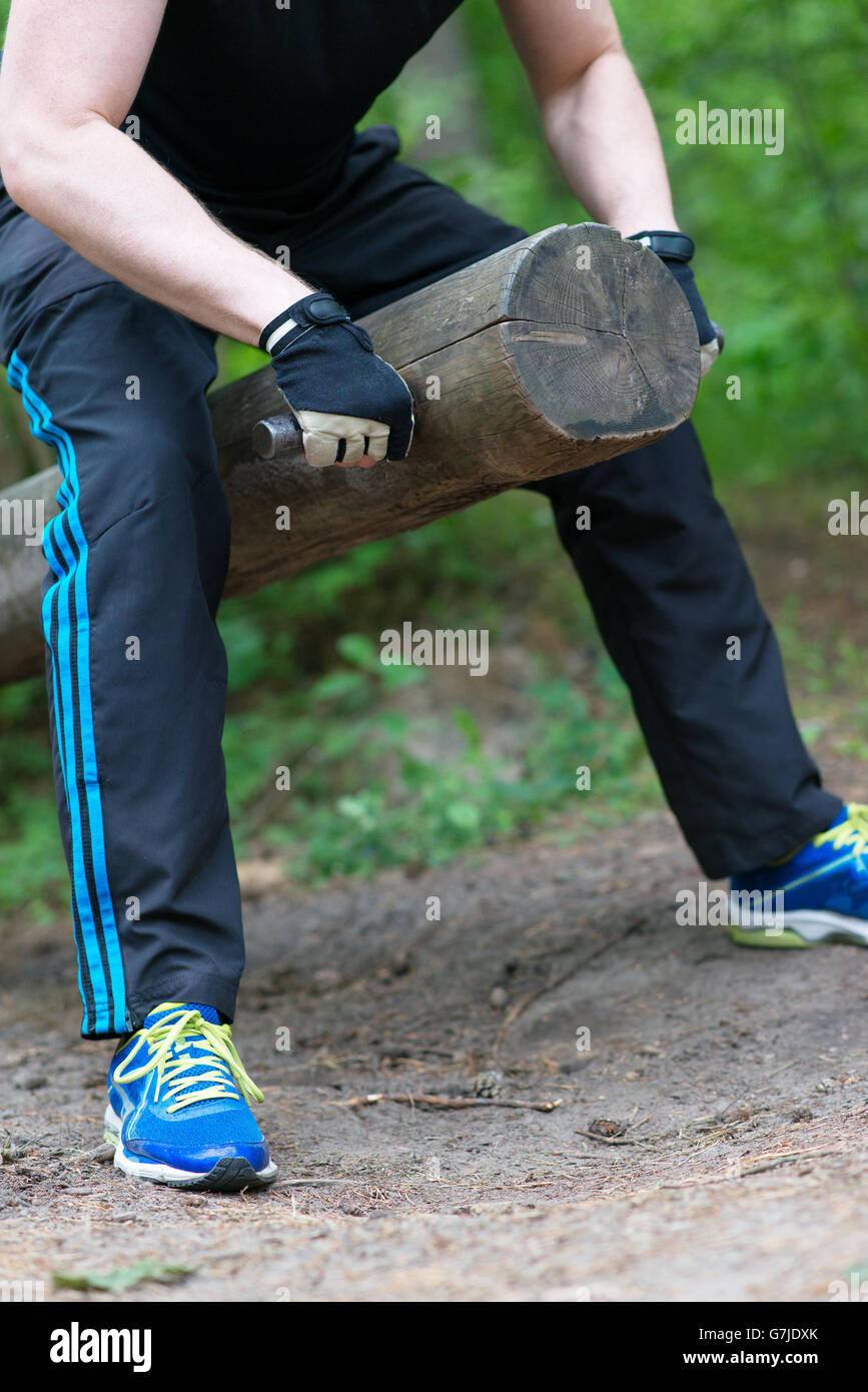 Man lifting log in the forest. Stock Photo