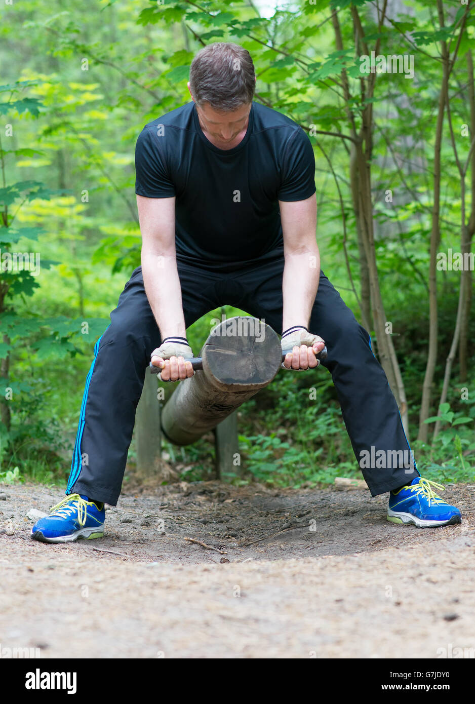 Man lifting log in the forest. Stock Photo