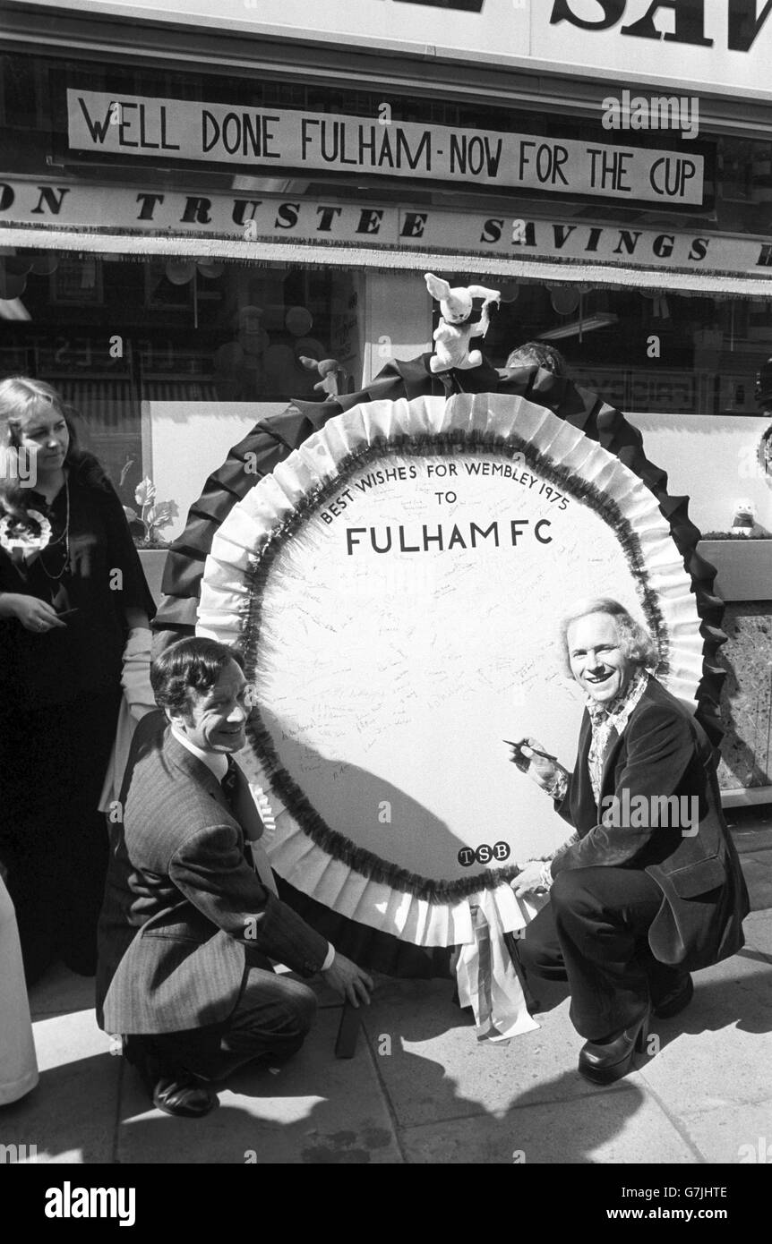 Bank manager Alan Perkins has made a rosette measuring 5ft for the people of Fulham to sign to wish Fulham FC the best of luck in the FA Cup Final against fellow Londoners West Ham United. Pictured is Alan Perkins and David Hamilton (r) who is signing the rosette. Stock Photo