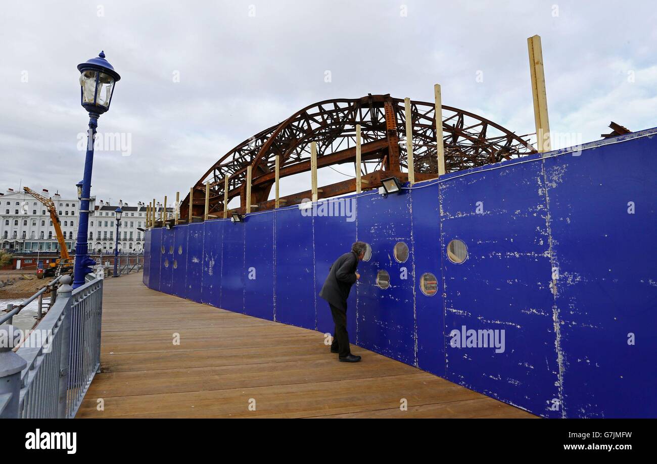 A man peers through a viewing window on Eastbourne Pier in East Sussex, as work continues to dismantle the steel carcass of the amusement arcade on the Grade II-listed pier which was left devastated by a fire earlier this summer. Stock Photo