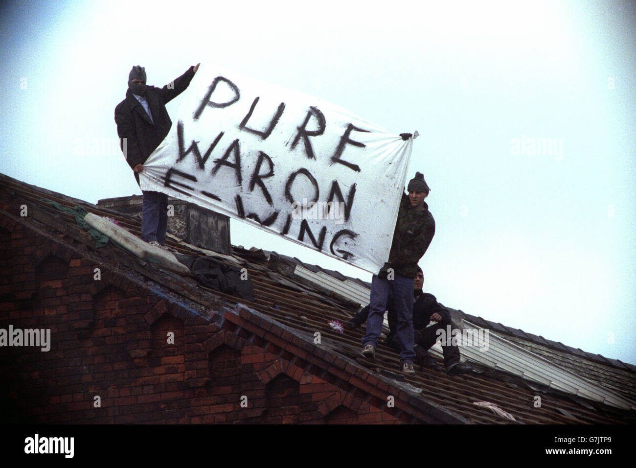 British Crime - Prison - Riots - Strangeways - Manchester - 1990. Prisoners display a banner declaring 'Pure war on E-Wing' on the roof of Strangeways prison. Stock Photo