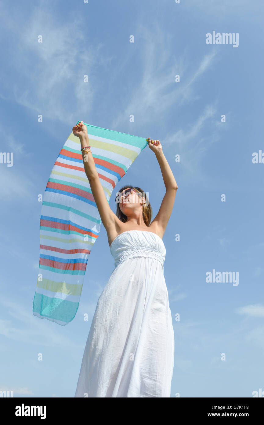 Girl waving a colorful scarf on seaside against blue sky Stock Photo