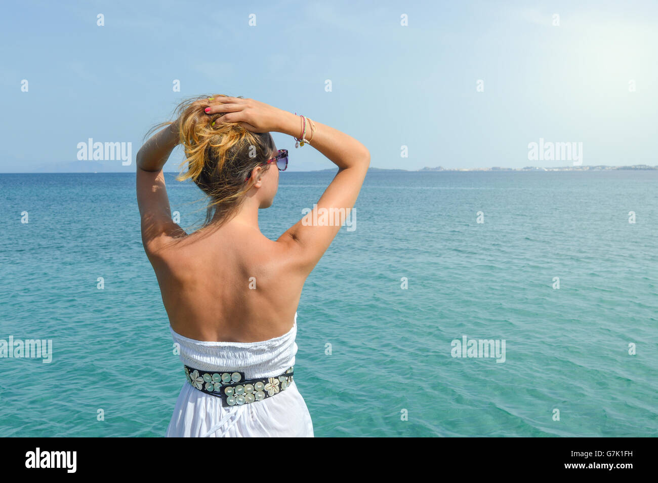 Tanned woman in dress facing seaside. Suumer vacation time Stock Photo