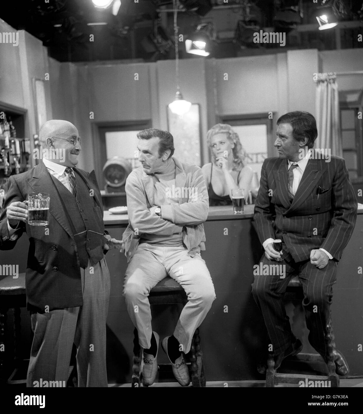 A bald Alf Garnett (Warren Mitchell) with The Foreman (Eric Sykes) and right Paki-Paddy (Spike Milligan) in a discussion on the election campaign during rehearsals for the 25-minute BBC One show called 'Up The Polls', which will be broadcast after the polls close at 10pm. Listening in to the discussion is actress Lorna Wile, who plays a barmaid. Stock Photo