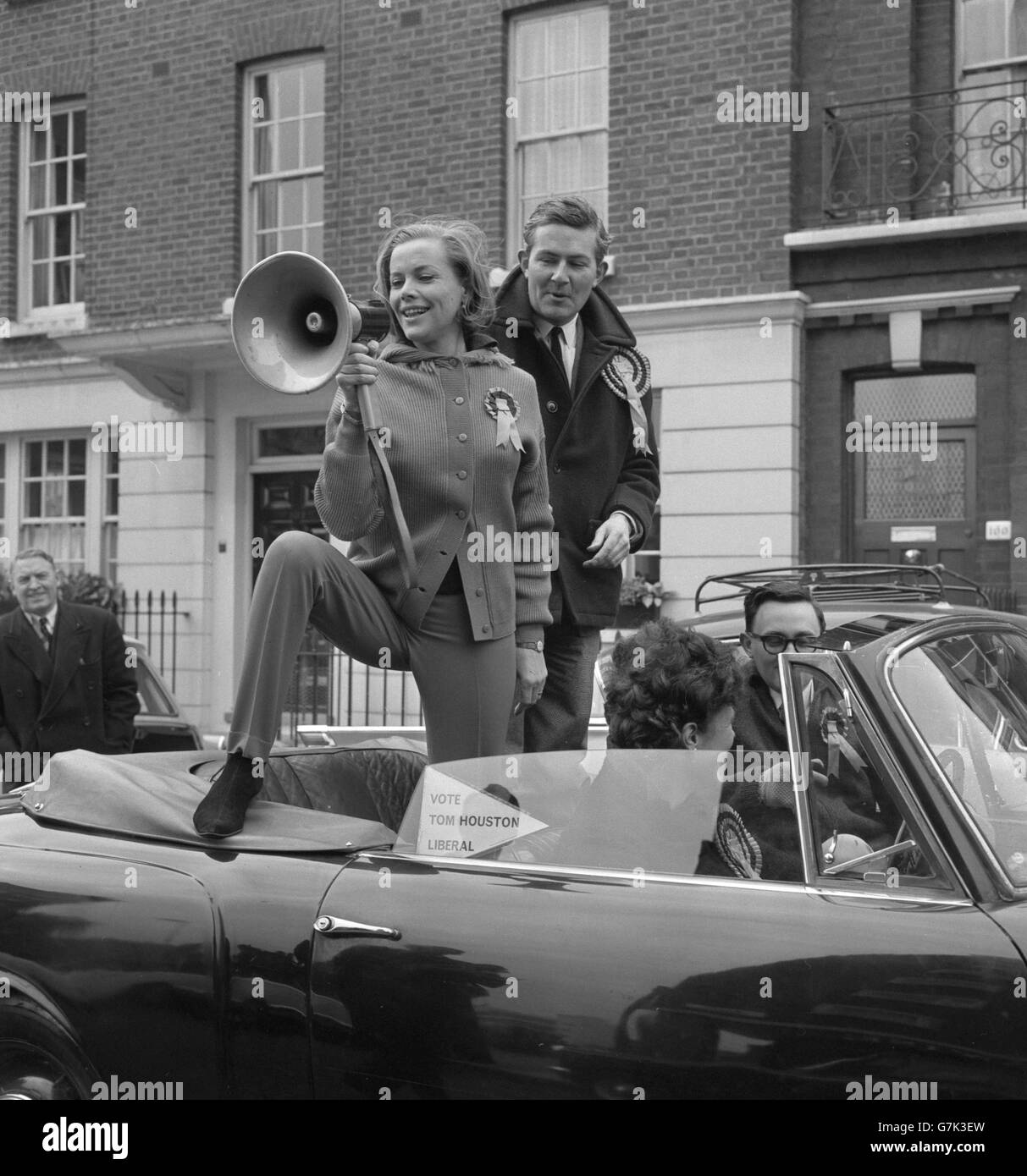Wearing a rosette, actress Honor Blackman - one-time Cathy Gale of The Avengers - takes up the loud hailer in support of Tom Houston, Liberal candidate for the Cities of London and Westminster in the General Election. Miss Blackman is with Houston when she joined a motorcade that toured the constituency as part of his election campaign. Stock Photo