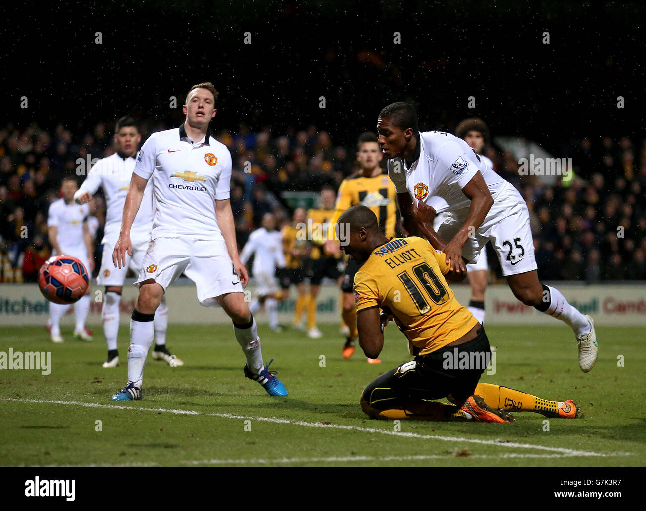 Cambridge United's Tom Elliot goes down in the area after battling for the ball with Manchester United's Antonio Valencia (right) Stock Photo