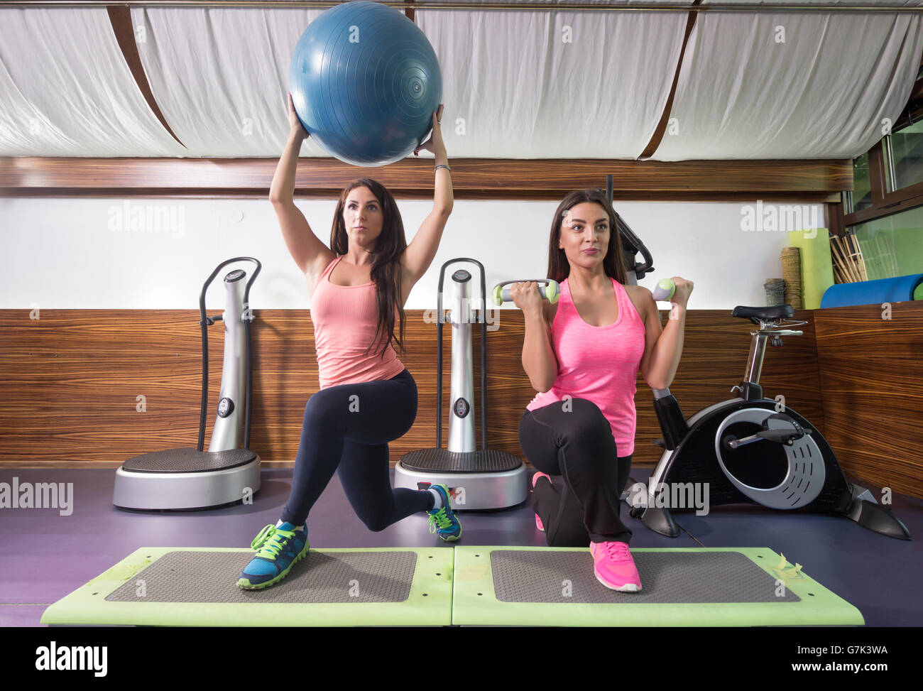 Two fit women exercise gym, lunge stepper, exercize ball, weights. Stock Photo