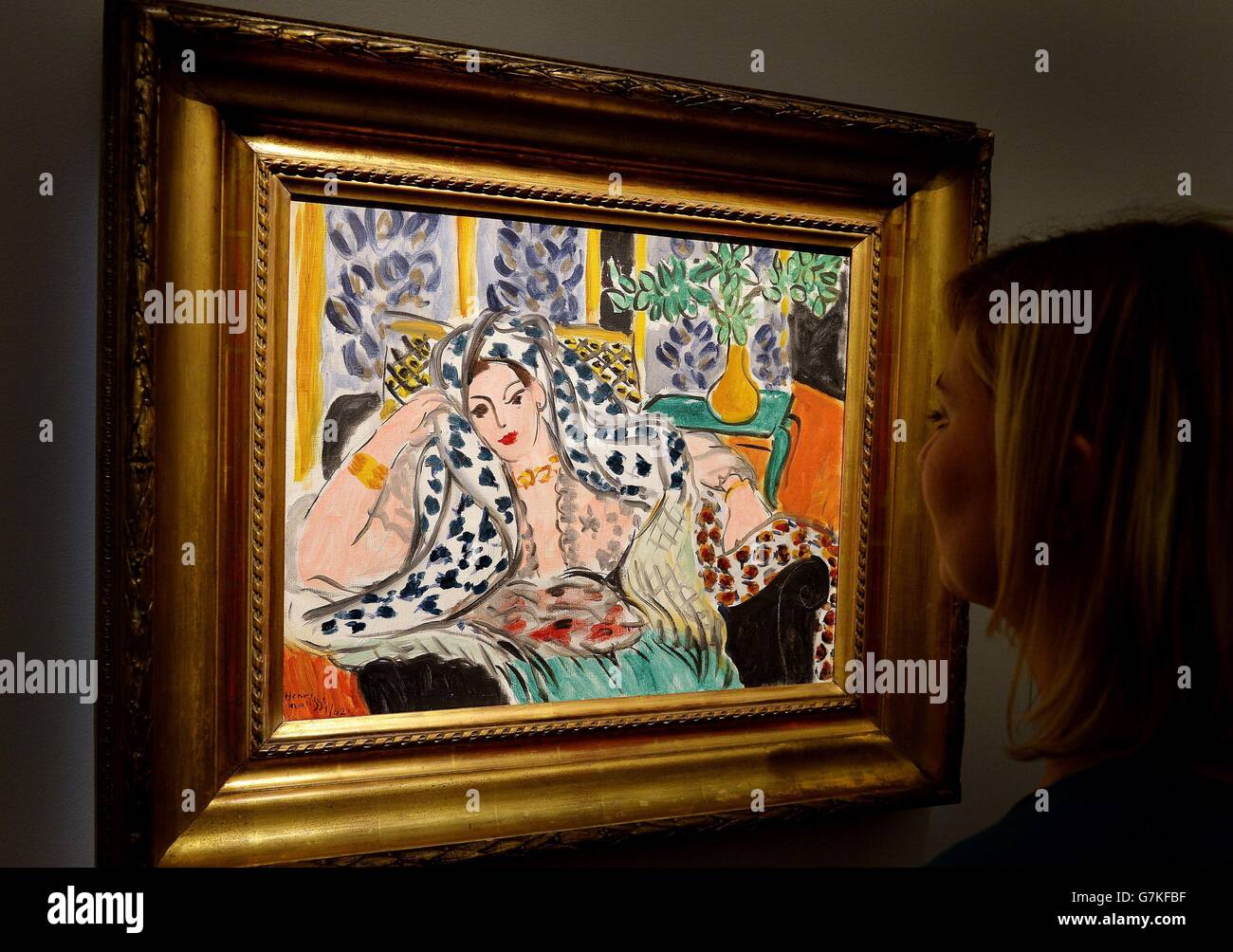 A young woman studies the Henri Matisse painting Odalisque au Fauteuil Noir, which is estimated to be sold for between £9 - 12 million during the Impressionist and Modern auction on 3rd February at Sotheby's, on display at their showrooms in central London. Stock Photo