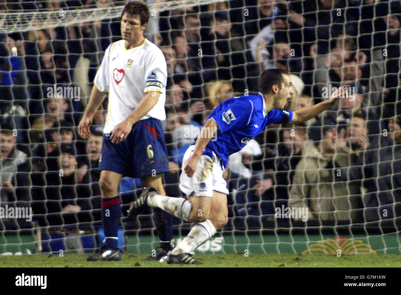 Everton's Leon Osman runs past Portsmouth captain Arjan De Zeeuw as he celebrates scoring the winning goal . Stock Photo