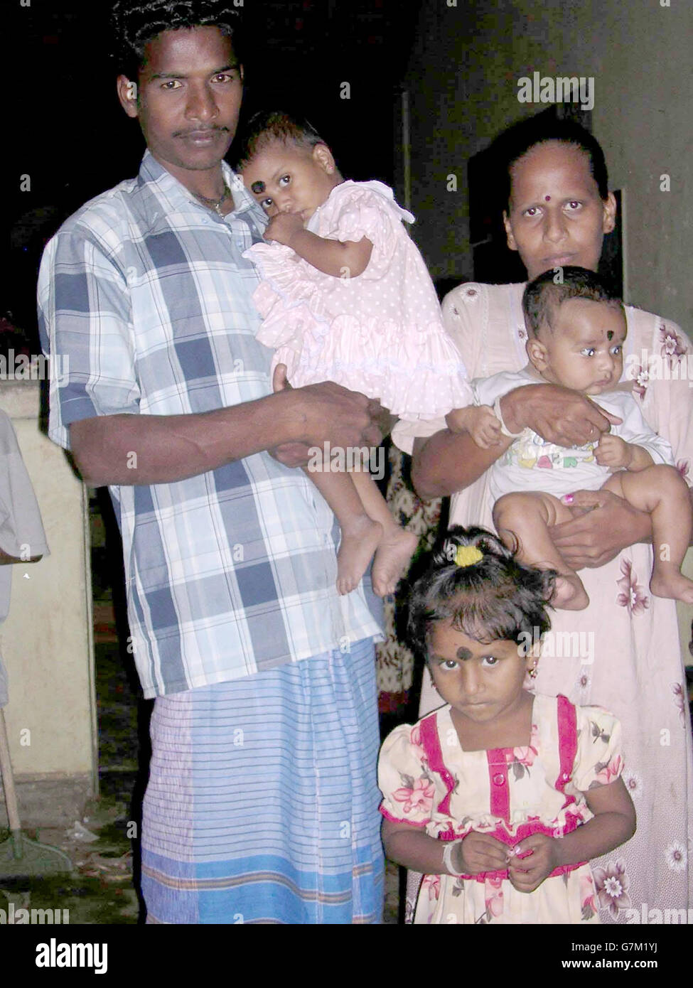 Premila Mirthanayagam, 23, and her husband Antonipillai, stand with their three children. Antonipillai carried two of the children and held onto a third as they fought through the waves. Stock Photo