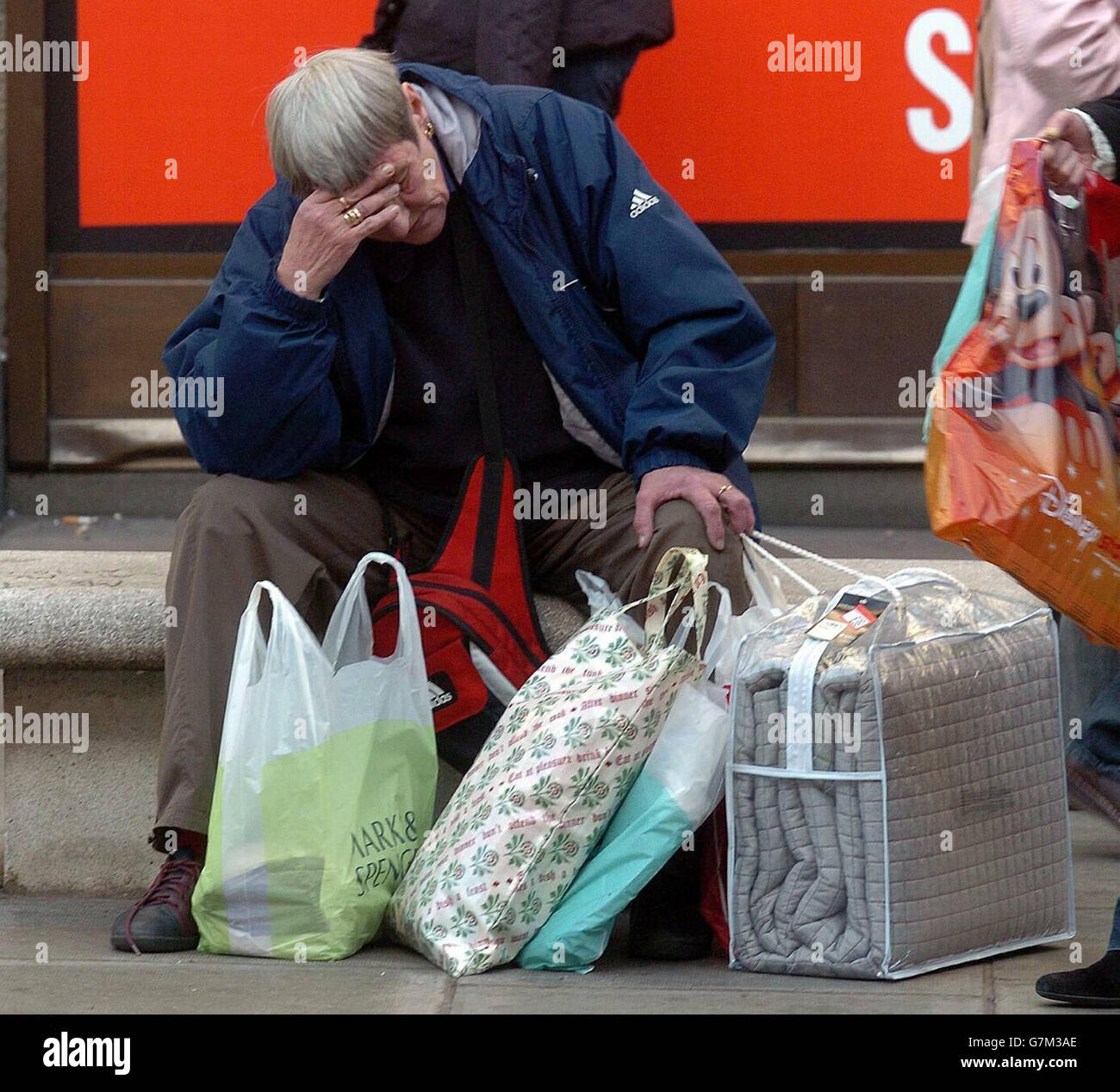 An exhausted shopper takes a break from shopping. Retailers have reported a brisk start to the festive sales period. Stock Photo