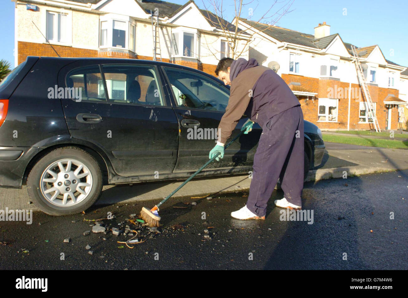 John Dunne sweeps fallen tiles which left his car badly damaged Stock Photo Alamy