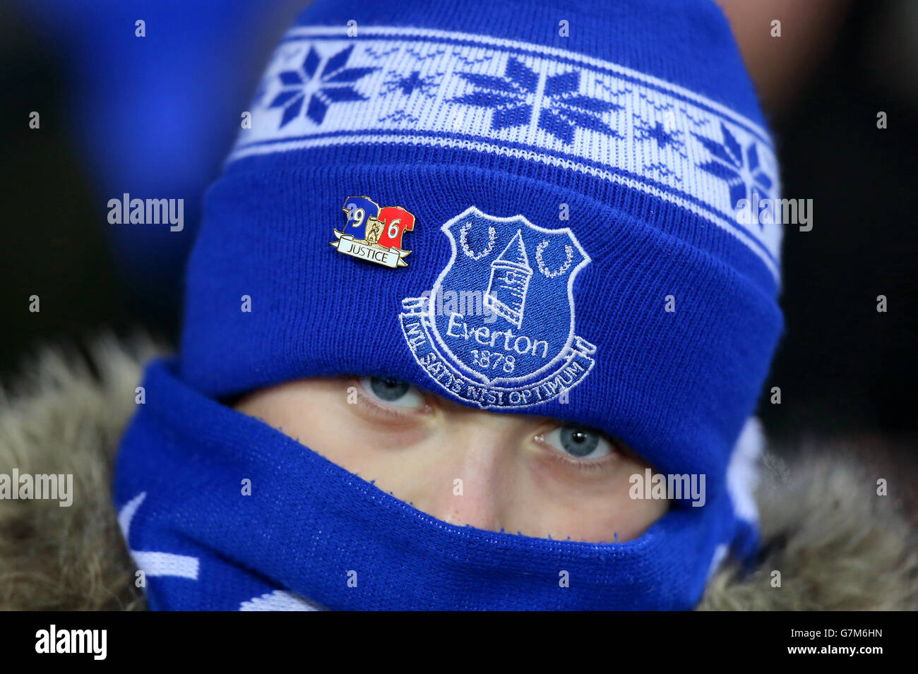 An Everton fan in the stands wearing a pin badge supporting the