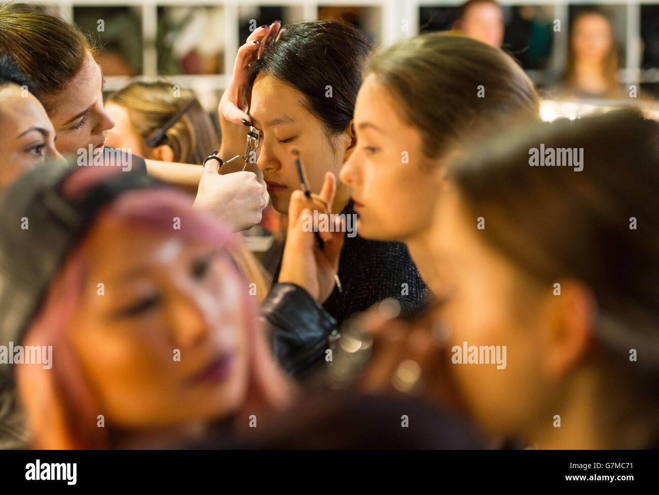 Models have their makeup applied backstage before the Bora Aksu catwalk show, at Somerset House, London, during London Fashion Week. Stock Photo