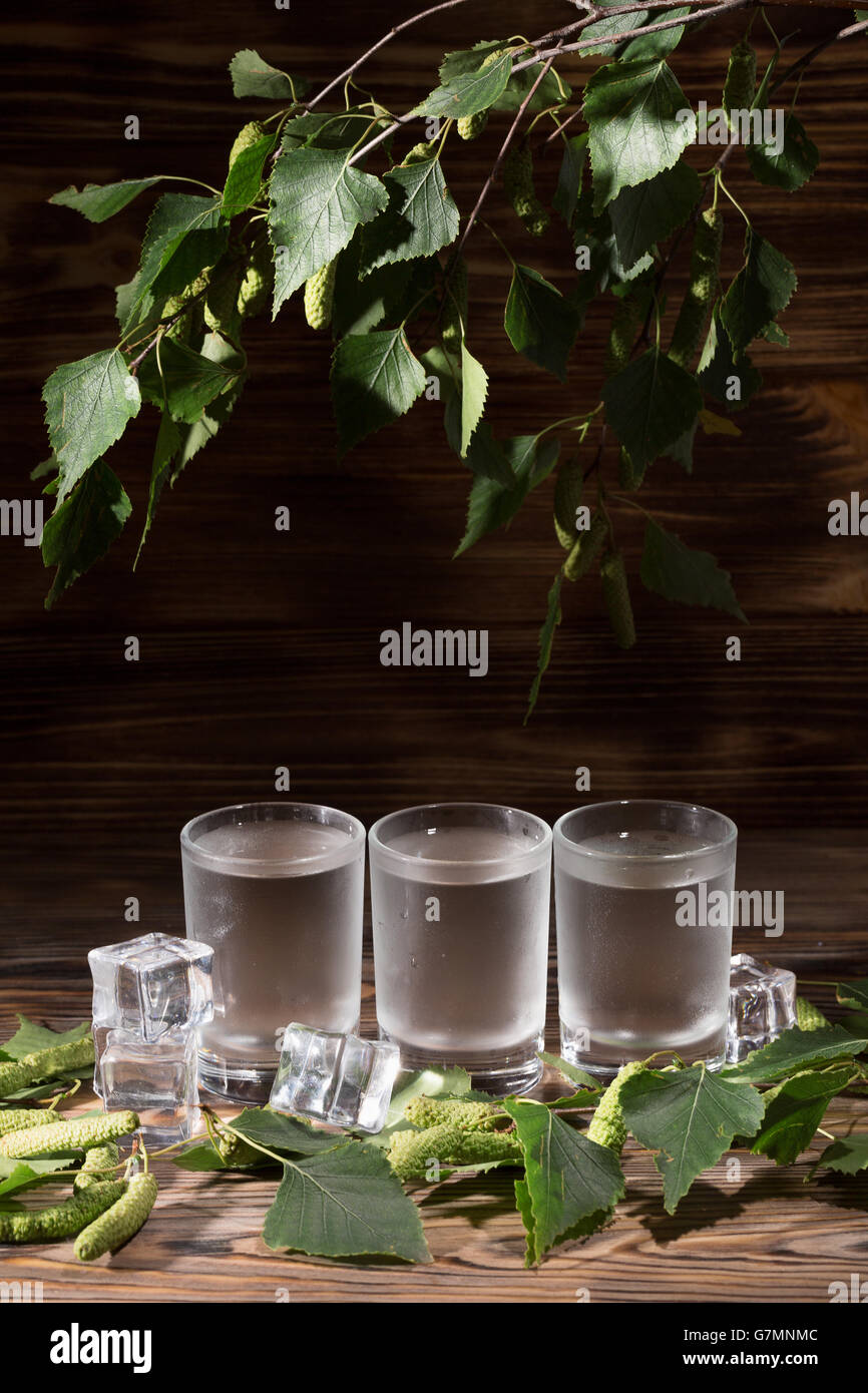 cold vodka on birch buds on the wooden background. Stock Photo