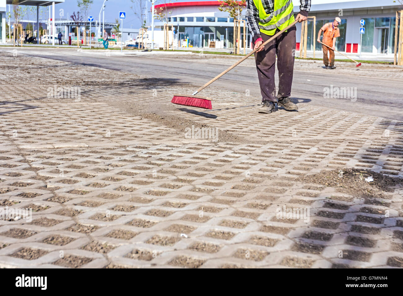 Worker sweeps urban space with a wide broom, brush cleaning Stock Photo