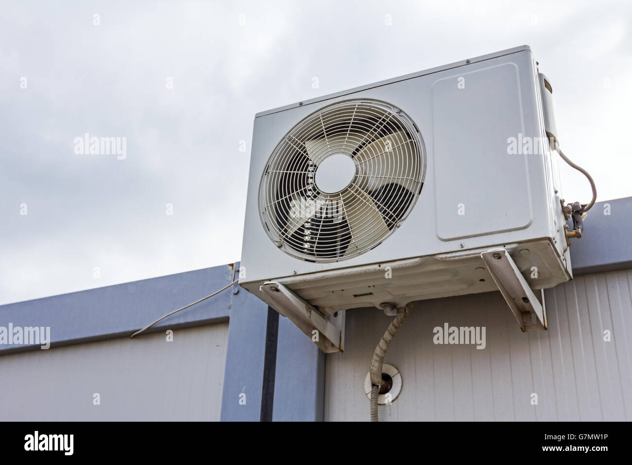 Outdoor unit, compressor, of air conditioner is placed on white container office. Stock Photo