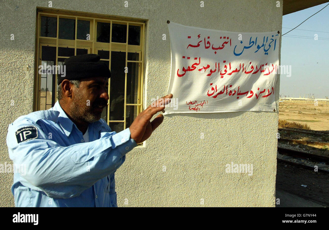 An Iraqi Police officer outside a check point in Umm Qasr, where a banner has been put up calling for support in voting for the United Iraqi Alliance in the national elections. Stock Photo