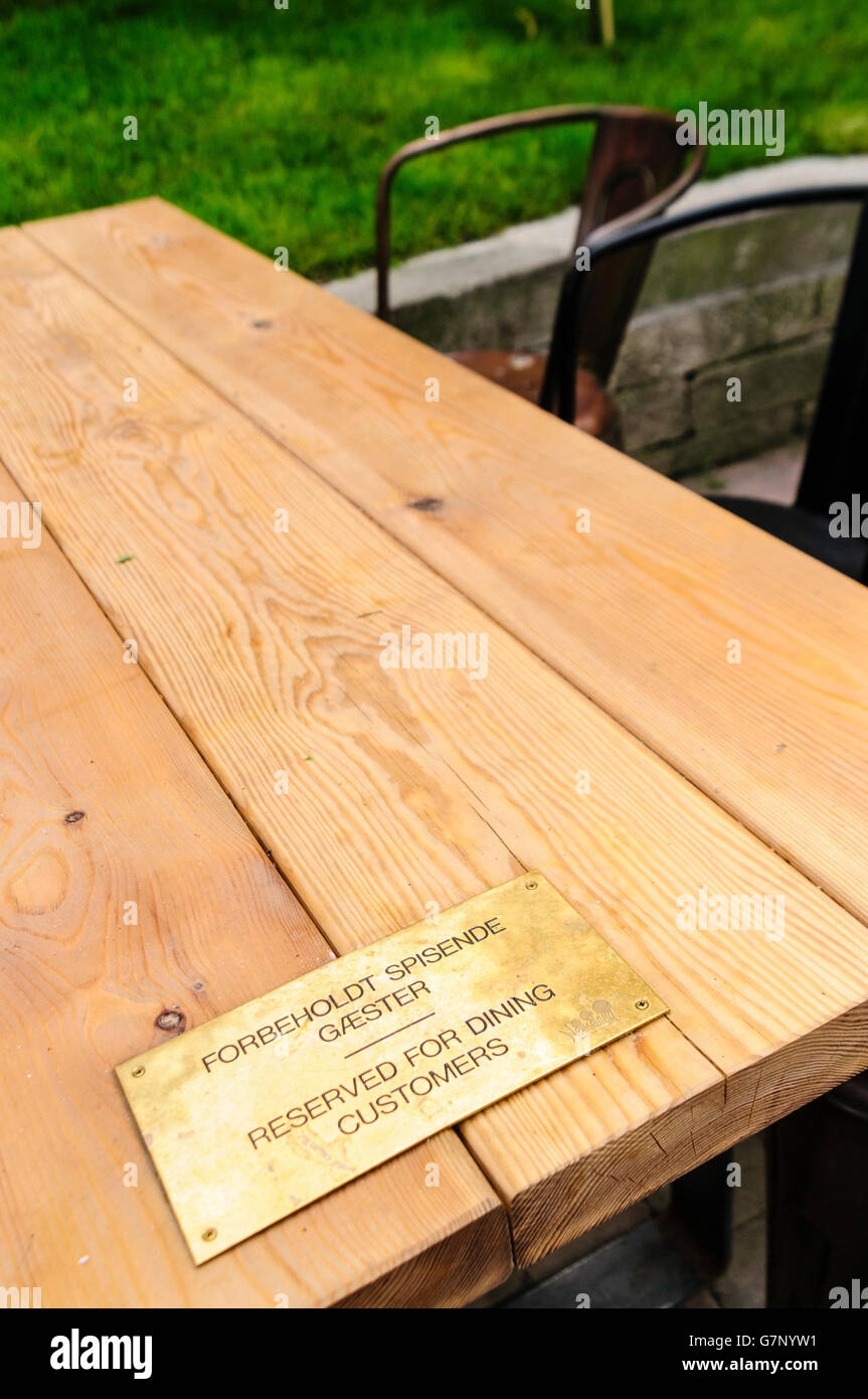 Sign on an outdoor table at a restaurant saying that it is reserved for dining customers in English and Danish Stock Photo