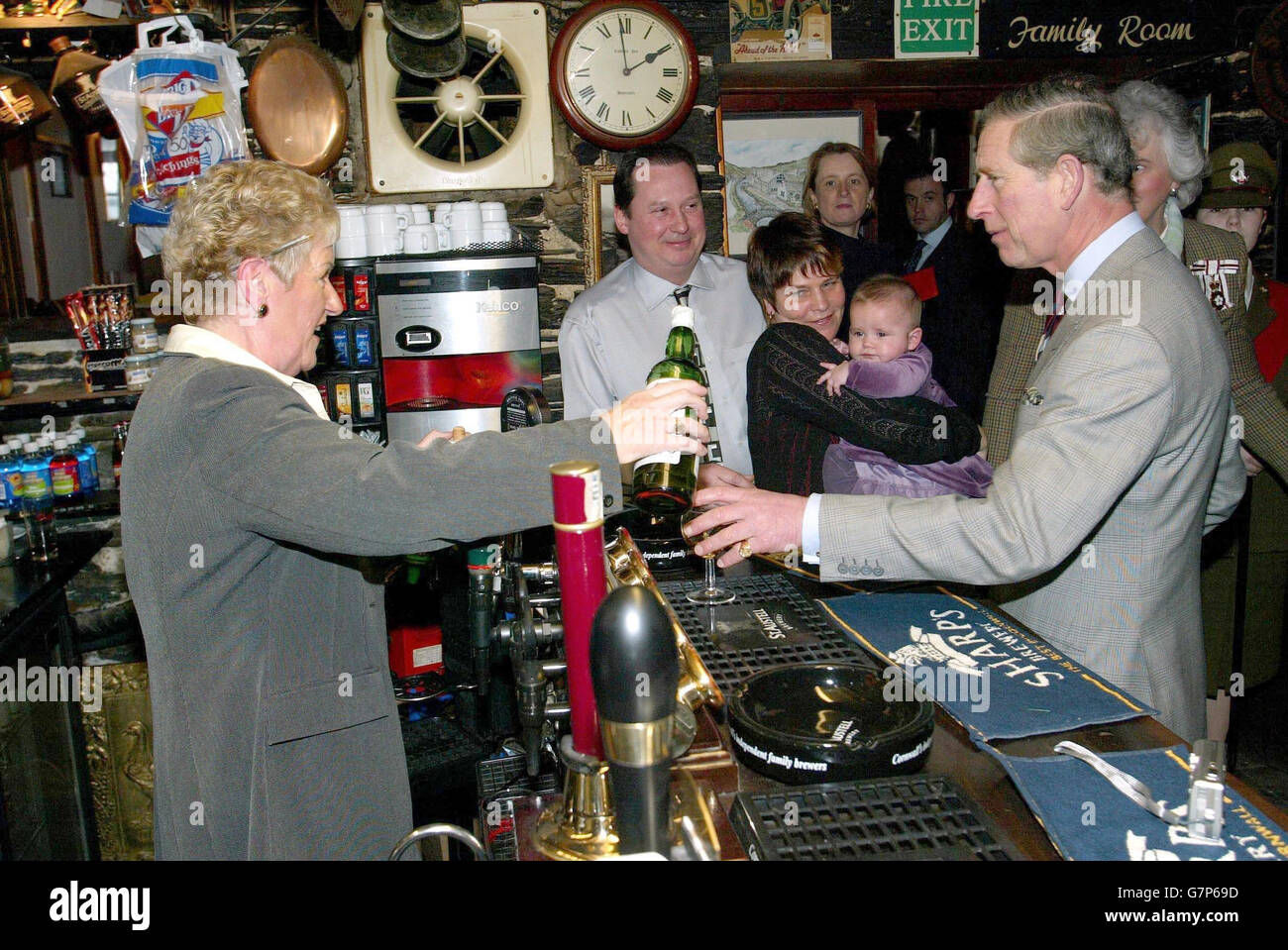 Landlord Adrian Bright, partner Tracy Menhenick and daughter Lily watch as barmaid Vall Hall serves a whiskey to His Royal Highness Prince Charles, at the Cobweb Inn during a visit to the flooded Cornish village of Boscastle. Stock Photo