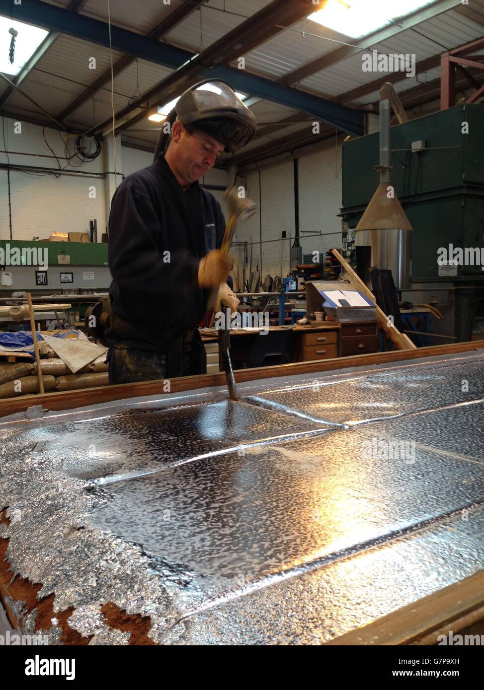 A worker cutting sheets of sandcast lead a process that dates back