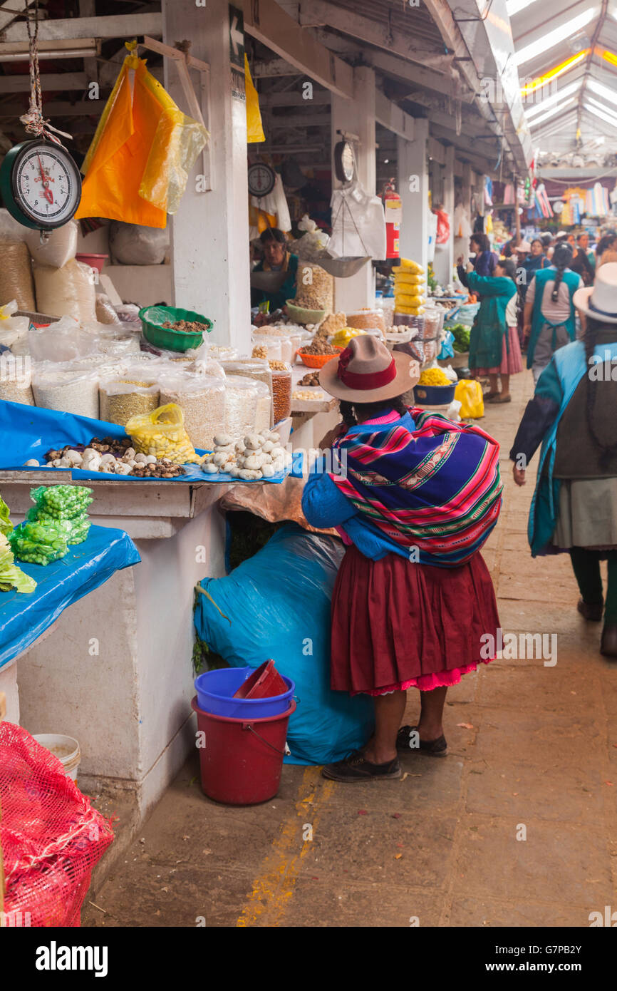 Short Peruvian woman buying dried beans and white potatoes at the San Pedro market in Cusco Stock Photo