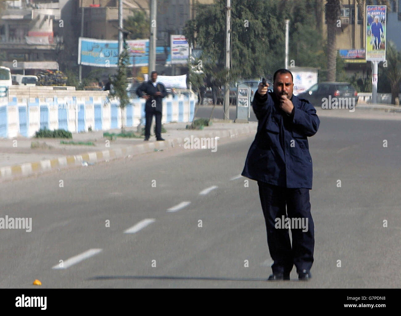 An Iraqi policeman points his pistol to oncoming traffic to stop people entering the southern Iraqi city of Basra without special driving permits. Stock Photo