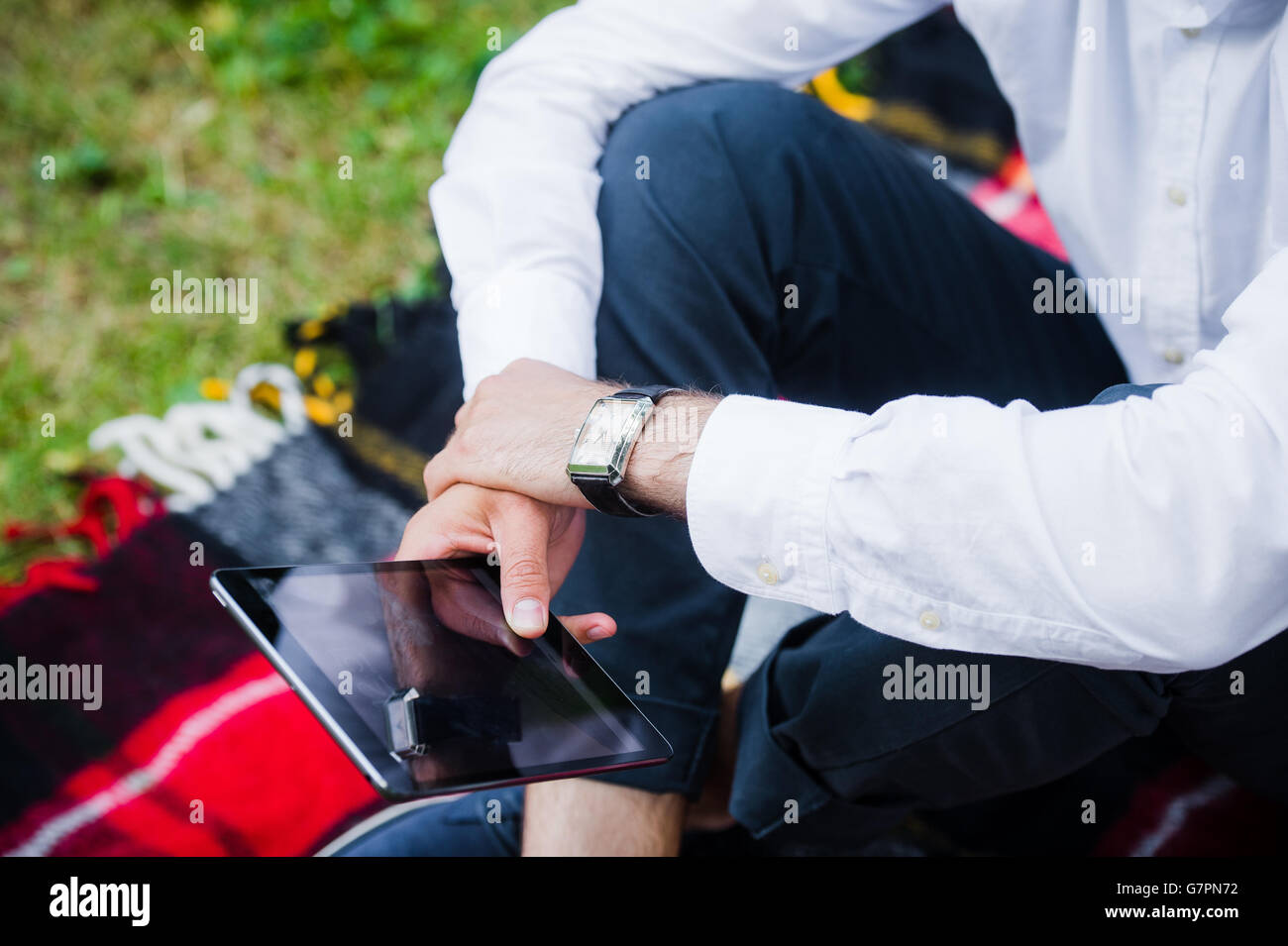 Young business man using tablet in a park. Close-up shot. Stock Photo