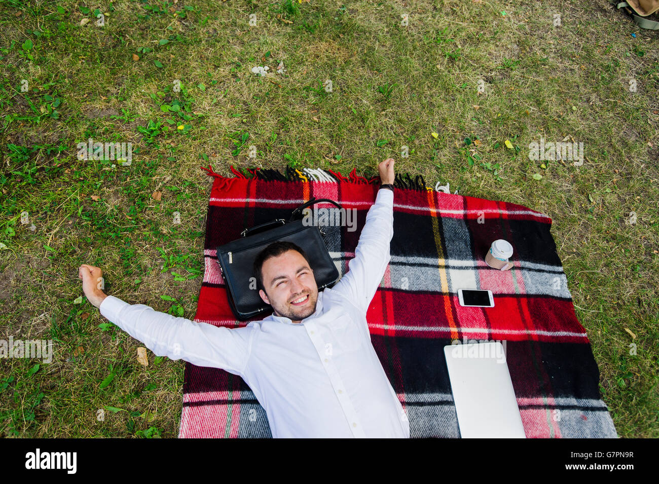 Image of businessman relaxing on the grass with laptop near by Stock Photo