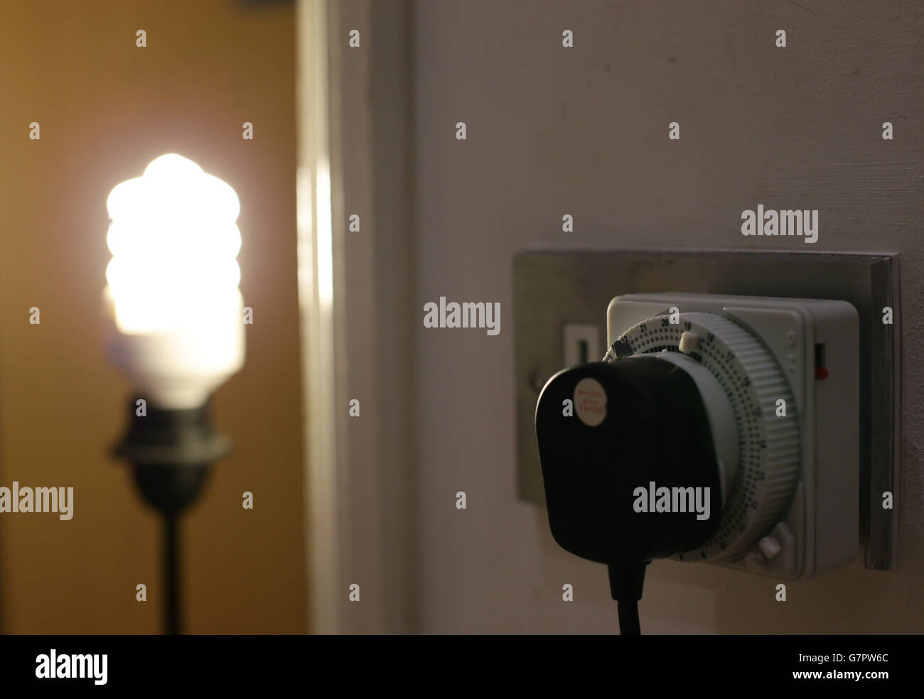 An energy saving light bulb is plugged into a timer switch, at a home ...