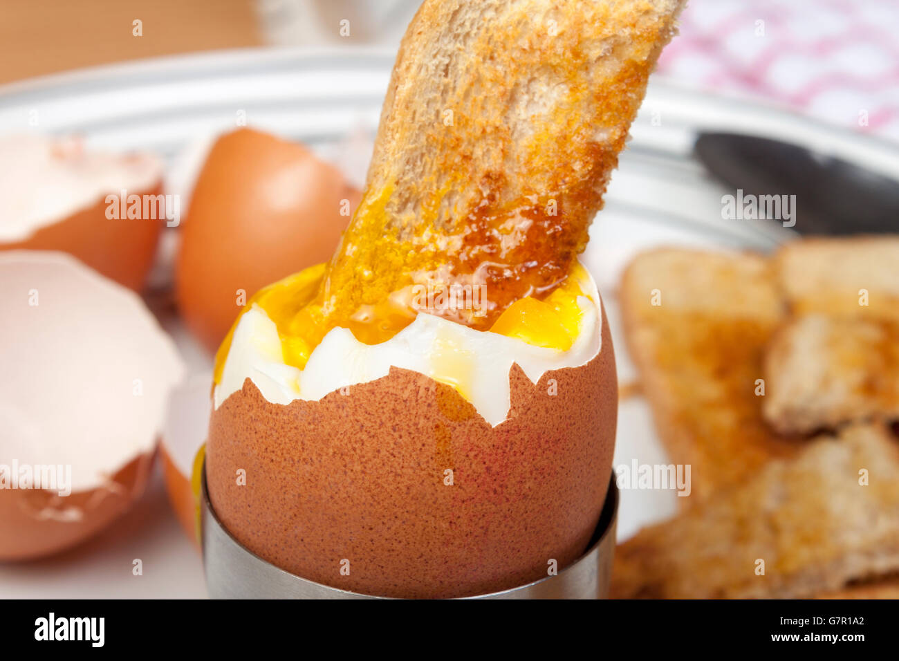 Close up shot of a golden toasted bread soldier dipped in a runny egg on a plate Stock Photo