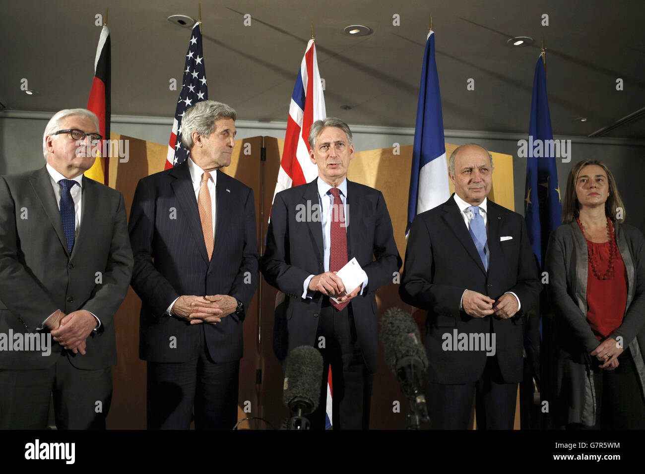 (left to right) Germany's Foreign Minister Frank-Walter Steinmeier, US Secretary of State John Kerry, Foreign Secretary Philip Hammond, French Foreign Minister Laurent Fabius and High Representative of the European Union for Foreign Affairs and Security Policy Federica Mogherini line up as Hammond reads a statement to waiting media following their talks at Heathrow Airport, London about the recently concluded round of negotiations with Iran over their nuclear program. Stock Photo