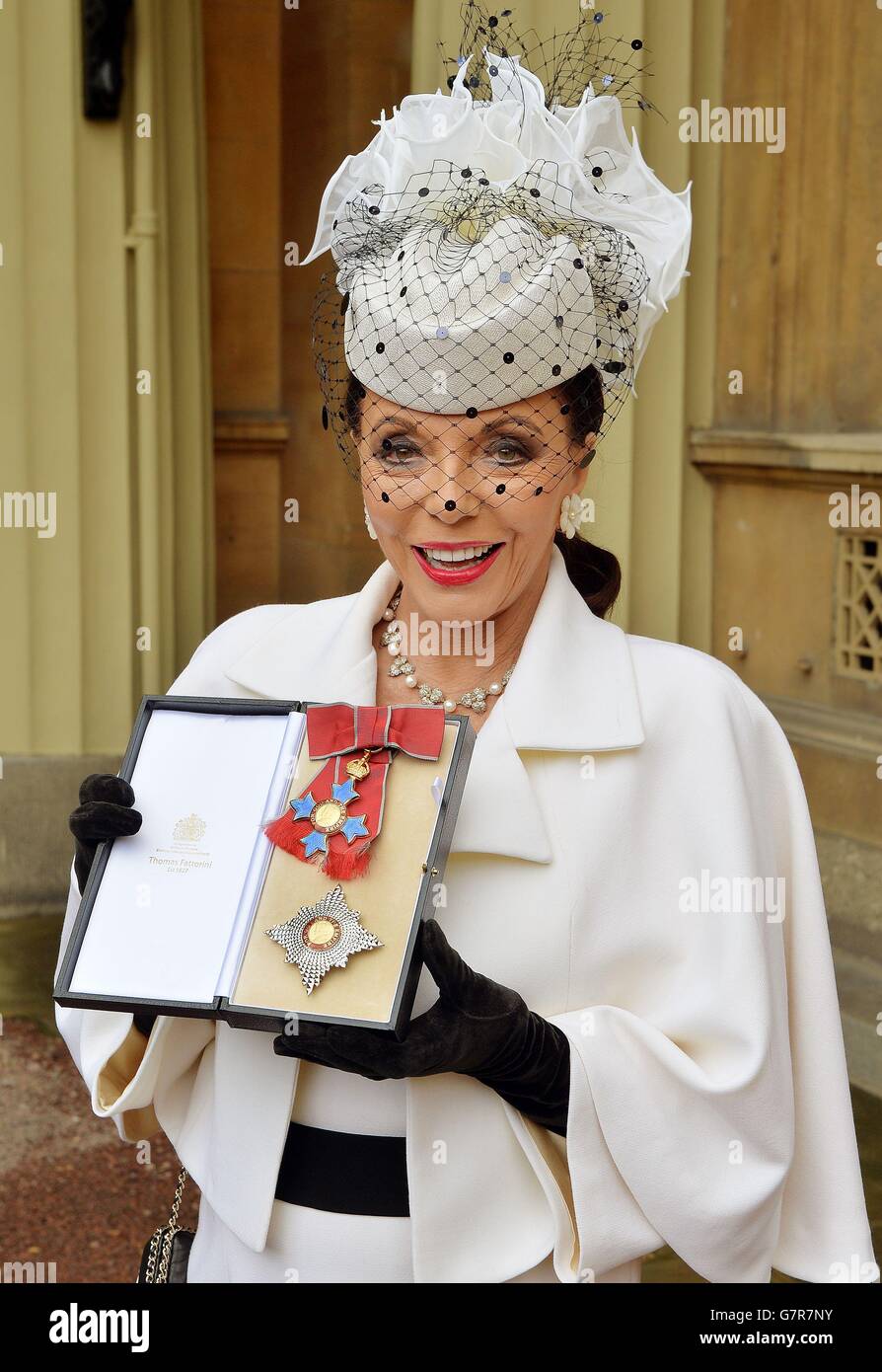 Dame Joan Collins holds her insignia of Dame Commander of the British