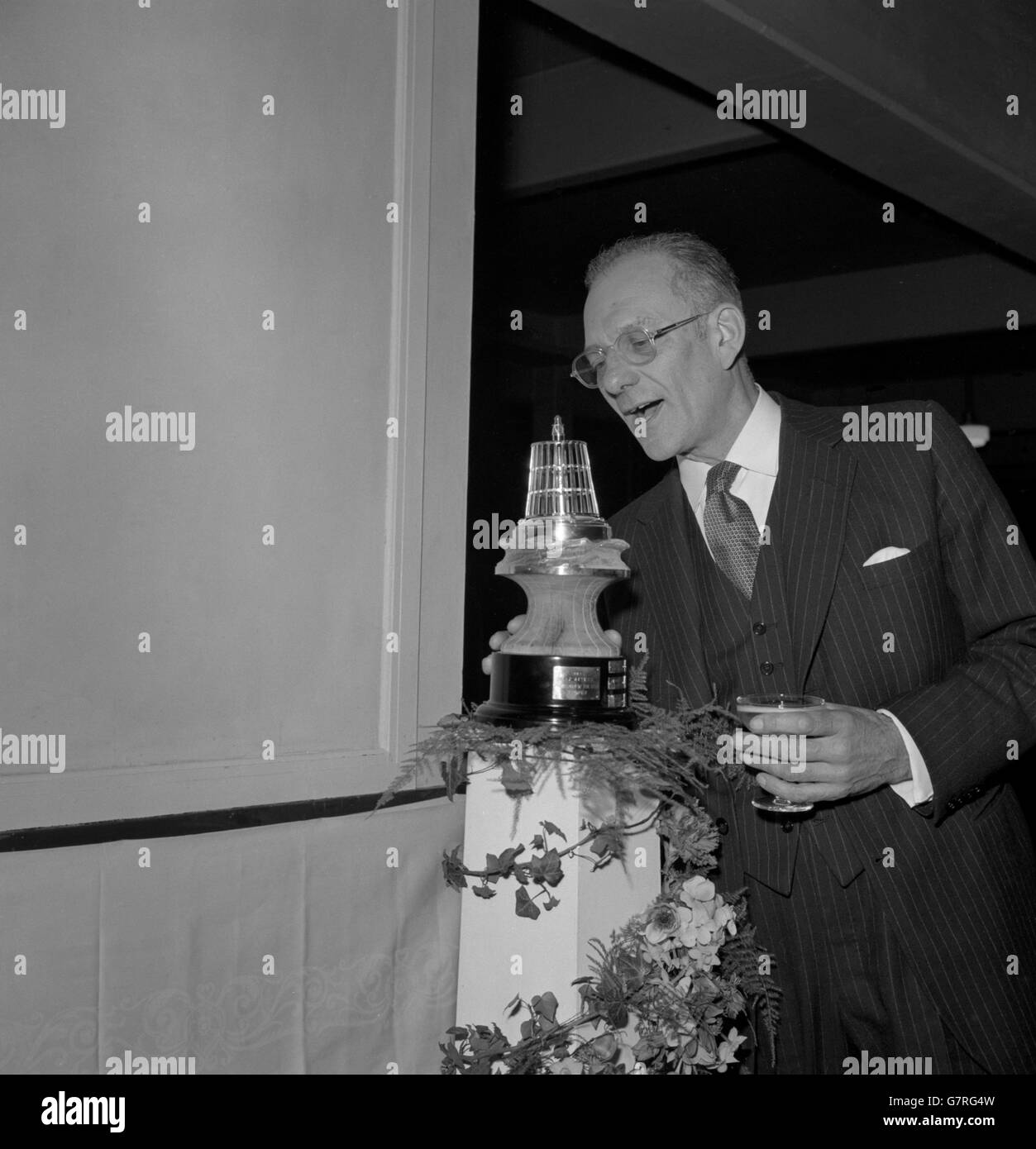 Glass in hand, 58 year old Francis Chichester exclaims with delight as he takes a close look at the Yachtsman of the Year award shortly after it had been presented to him at the Boat Show at Earl's Court, London. Francis Chichester, from Barnstaple, will be remembered for his success with a 39 foot yacht which he sailed alone to win the transatlantic race from England to America in July last year. Stock Photo