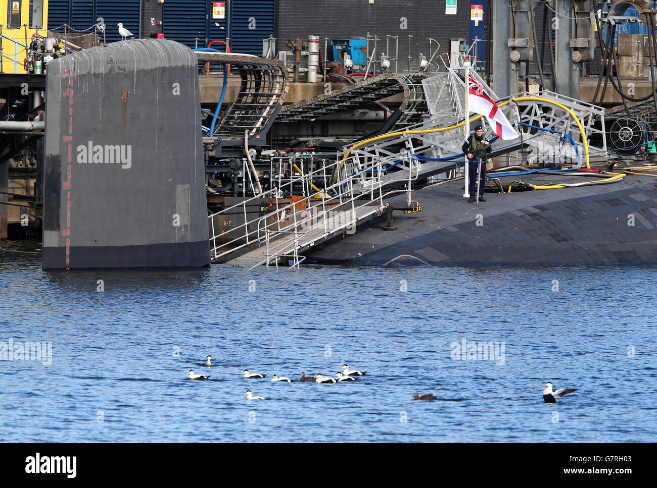 A soldier at the rear of HMS Victorious a Vanguard-class submarine at its base at HM Naval Base Clyde. Stock Photo