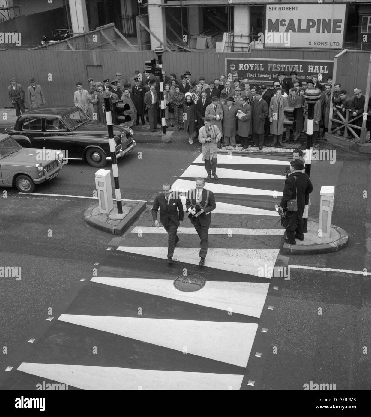 Ernest Marples, Minister of Transport, and A. C. Dennis, Mayor of Lambeth, are the first to use the new Panda pedestrian crossing at York Road, outside Waterloo Station. The minister had just inaugurated the crossing, first of the new type to operate in London. The Panda crossings, to be tried for an experimental 12 month period, have flashing warning lights operated by push button controls. They have blunted chevron markings on the carriageway and black and amber striped beacons. Stock Photo