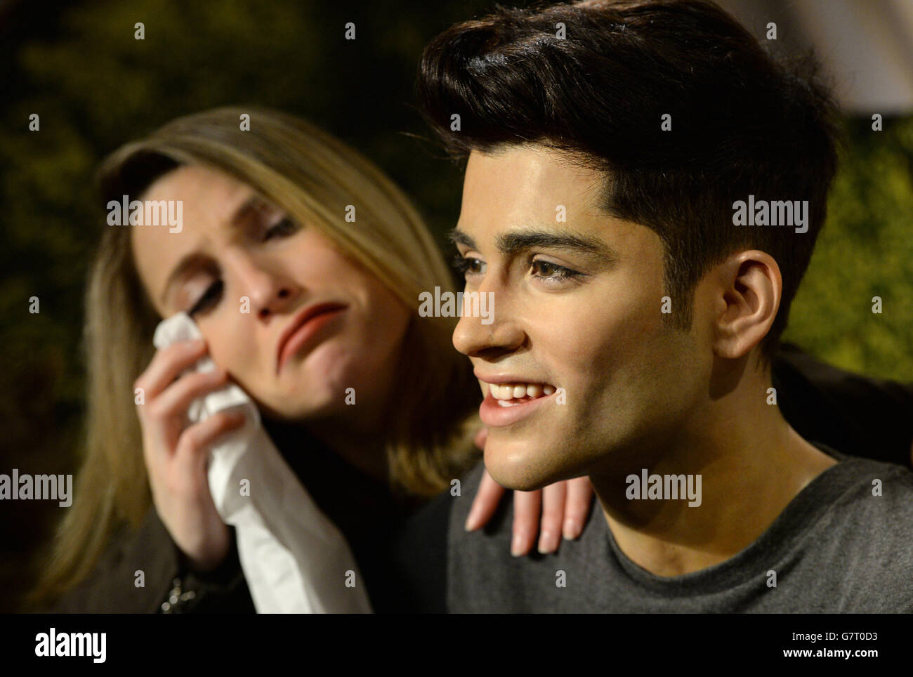 One Direction fan Lindsay Ringette appears upset while posing with the wax figure of former One Direction star Zayn Malik at Madame Tussauds, London. Stock Photo