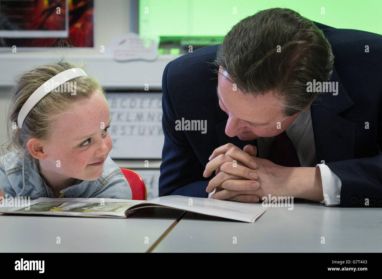 Prime Minister David Cameron helps with a reading lesson at the Sacred Heart Roman Catholic Primary School in Westhoughton near Bolton with six year old Lucy Howarth, while on the General Election campaign trail. Stock Photo