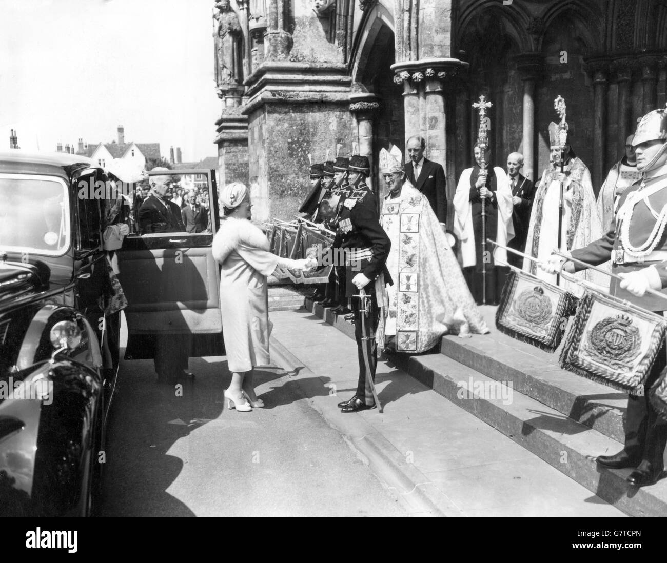 The Queen Mother is welcomed by Lord Herbert while the Archbishop of Canterbury, Dr. Geoffrey Fisher, waits to receive her on her arrival at Salisbury Cathedral to commemorate its 700th anniversary. About 3,000 people were present. The Queen Mother had driven from Cranborne, where she is staying with the Marquess and Marchioness of Salisbury. Stock Photo